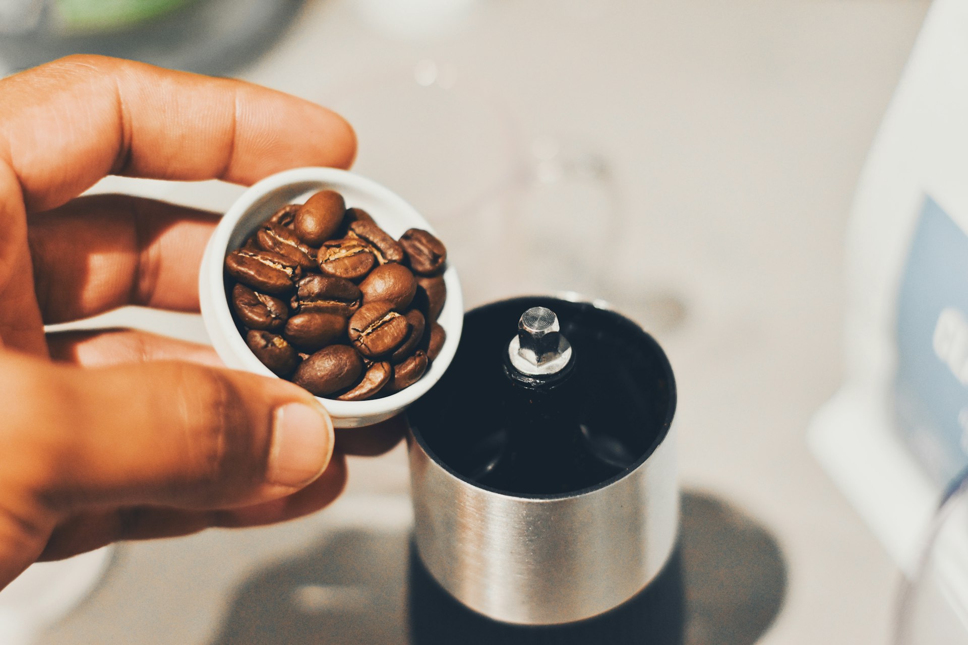 a person is holding a cup with coffee beans in it